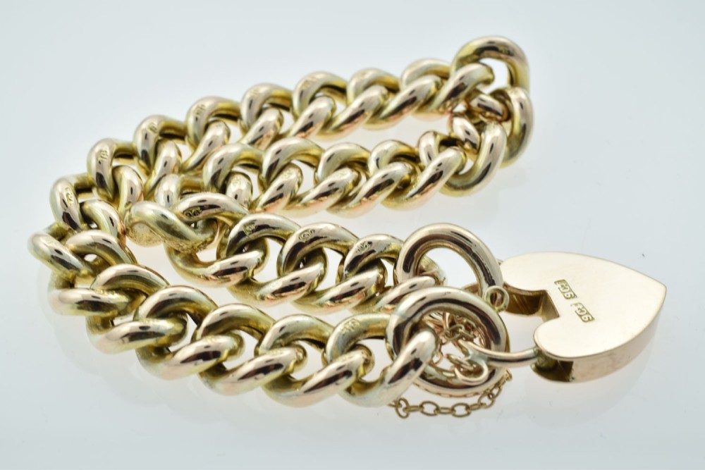 An antique 9ct gold curb link bracelet featuring half-engraved links, a heart-shaped padlock clasp, and an attached safety chain. View VII