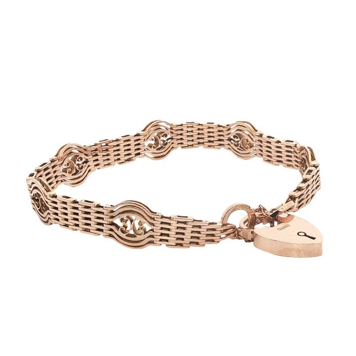 An antique 9ct rose gold gate link bracelet featuring openwork scroll panels, a heart padlock clasp, and a safety chain. View IV