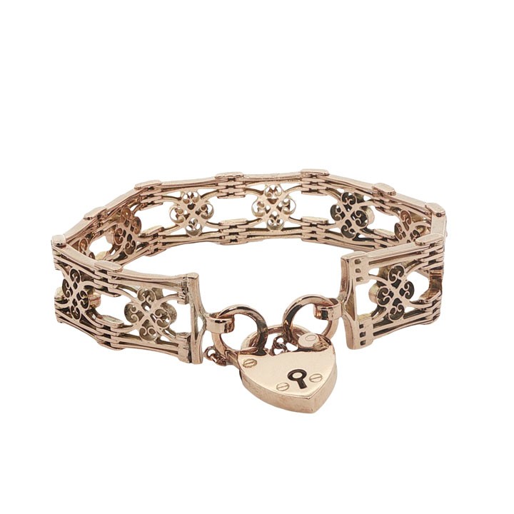 An antique 9ct rose gold gate link bracelet featuring decorative openwork filigree panels and a heart-shaped padlock clasp.