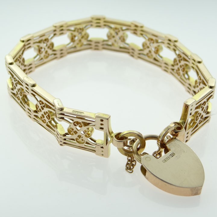 An antique 9ct rose gold fancy gate link bracelet featuring pierced scrollwork panels and a heart padlock clasp with a safety chain. View IV