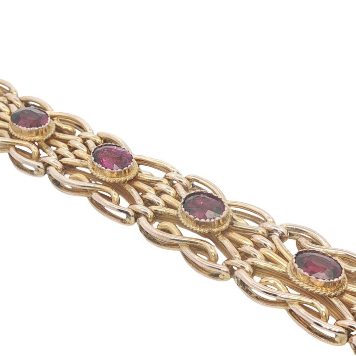An antique 9ct rose gold link bracelet featuring oval-cut almandine garnets set in ornate scrollwork links with a box clasp. View II