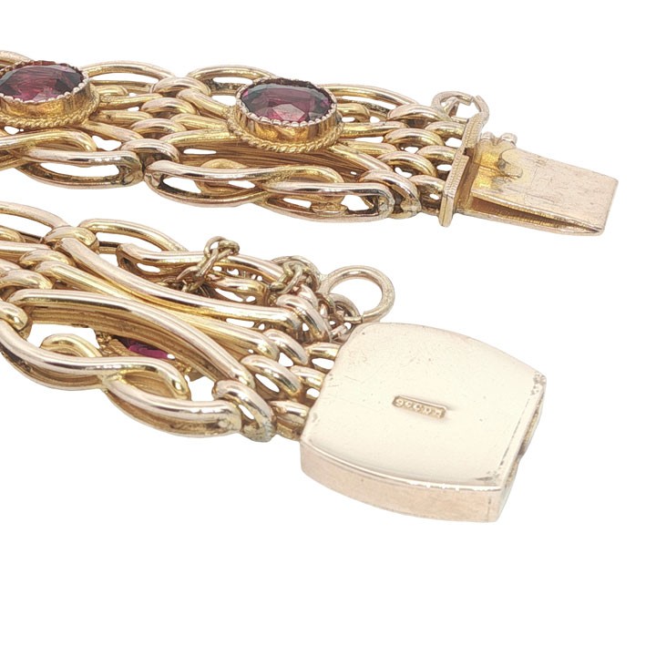 An antique 9ct rose gold link bracelet featuring oval-cut almandine garnets set in ornate scrollwork links with a box clasp. View IV