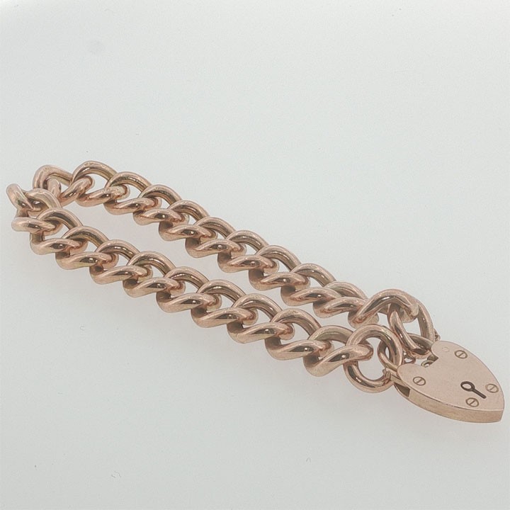 An Edwardian 9ct rose gold curb link bracelet featuring a heart-shaped padlock clasp and safety chain. View V