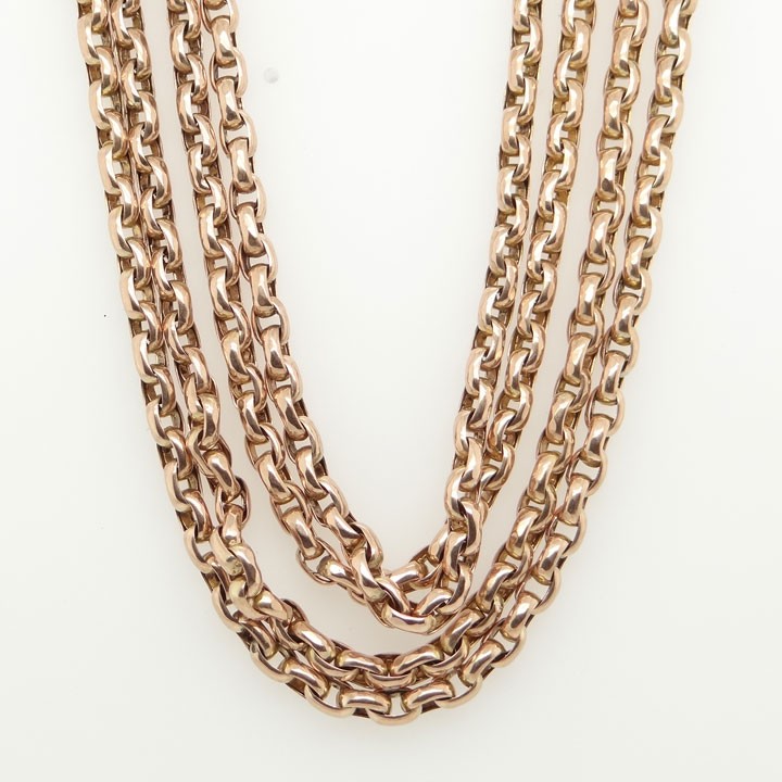 An antique 9ct rose gold long guard chain composed of uniform belcher links folded into multiple strands.