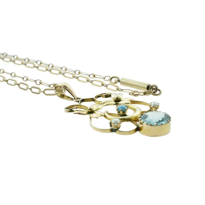 An antique 9ct rose gold openwork pendant featuring a crescent moon motif set with turquoise, seed pearl accents, and a central round faceted blue topaz drop. View IV
