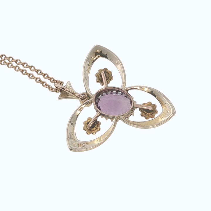 An Edwardian 9ct gold openwork pendant featuring a central oval amethyst surrounded by delicate seed pearls on a fine chain. View VI