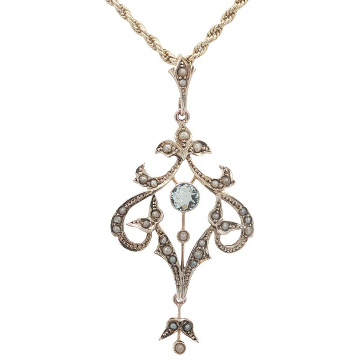 An openwork 9ct yellow gold Edwardian pendant set with a central round aquamarine and embellished with small seed pearls throughout. View II