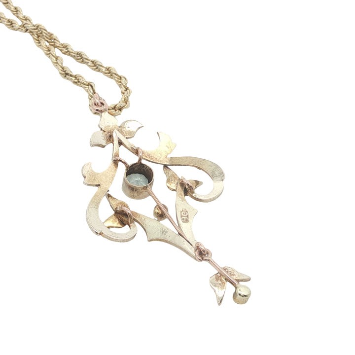 An openwork 9ct yellow gold Edwardian pendant set with a central round aquamarine and embellished with small seed pearls throughout. View III