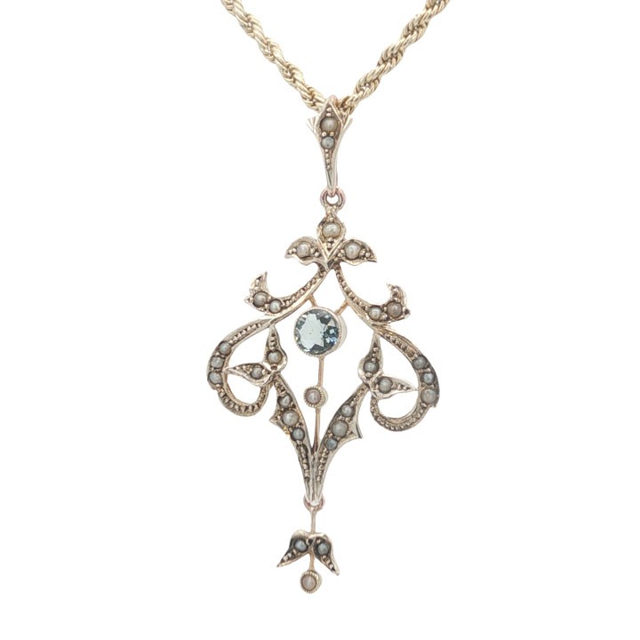 An openwork 9ct yellow gold Edwardian pendant set with a central round aquamarine and embellished with small seed pearls throughout. View V