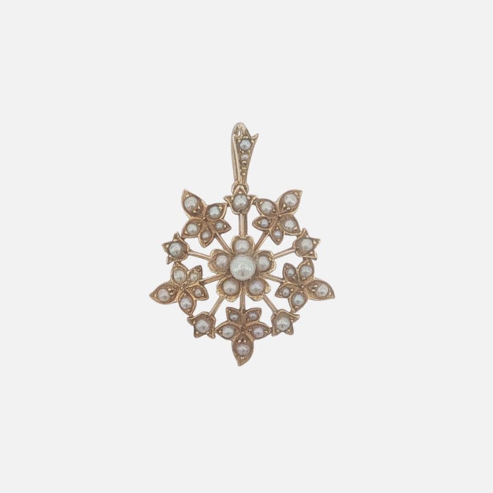 A late Victorian 15ct gold starburst pendant set with central and accent seed pearls forming a floral motif.