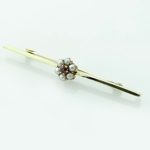 An antique yellow gold bar brooch featuring a central flower cluster set with a crimson almandine garnet and surrounding white seed pearls. View III