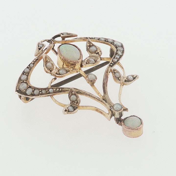 An Edwardian 9ct yellow gold openwork pendant featuring a central oval cabochon opal framed by leaf motifs set with seed pearls. View II