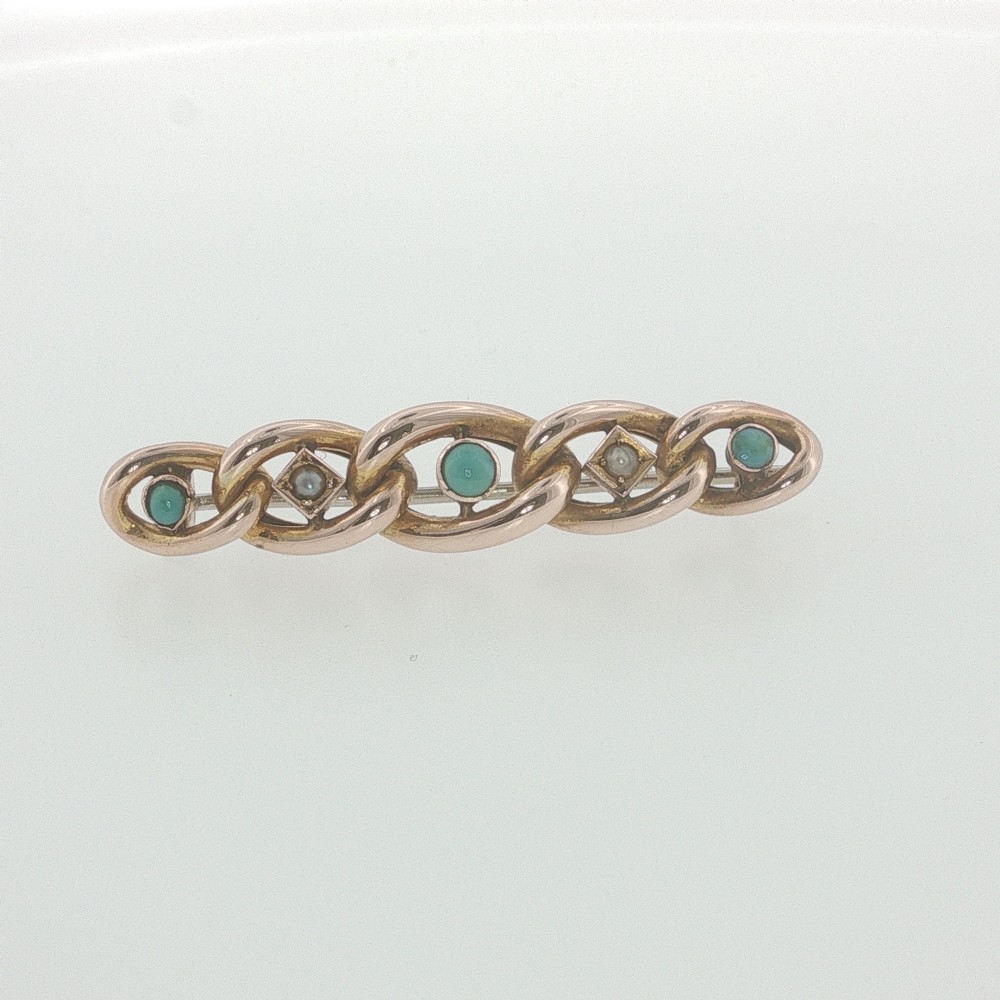 An antique 9ct rose gold bar brooch with curb links set with turquoise cabochons and seed pearls resting in a fitted presentation box. View II