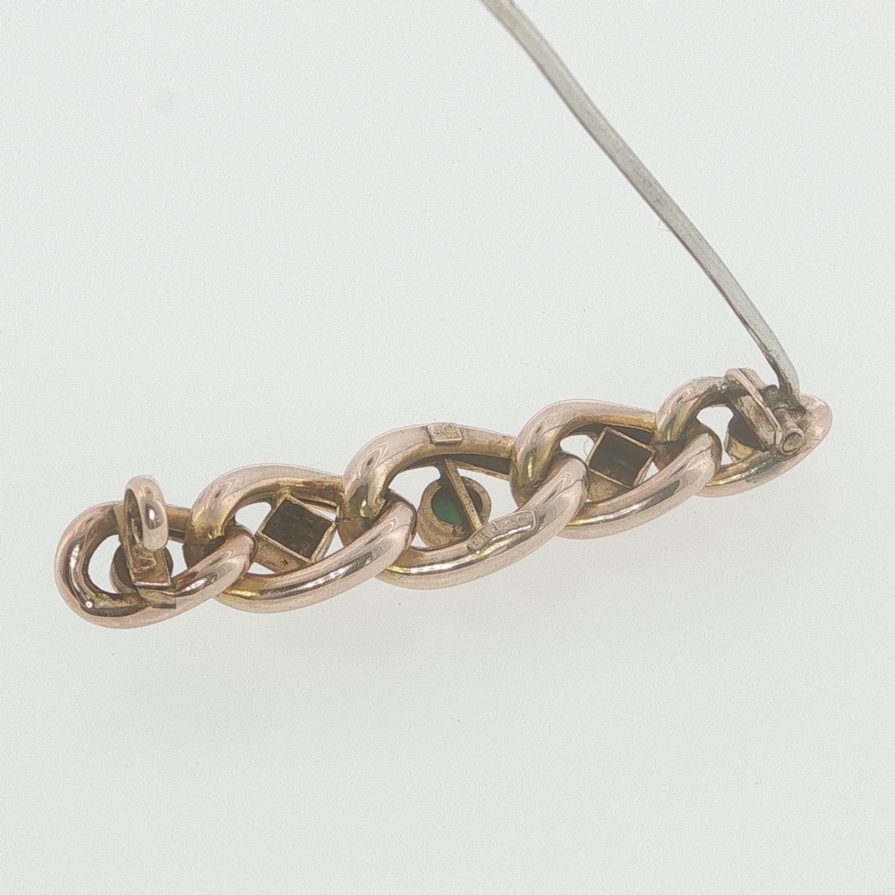 An antique 9ct rose gold bar brooch with curb links set with turquoise cabochons and seed pearls resting in a fitted presentation box. View IV