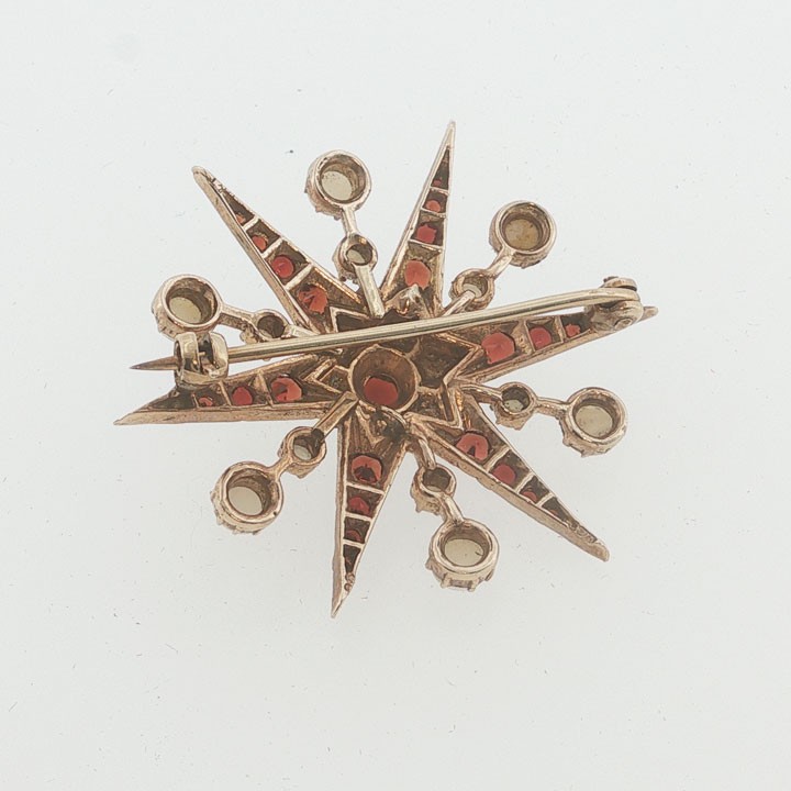 A 9ct yellow gold starburst brooch set with a central round garnet, surrounded by radiating point rays set with smaller garnets and seed pearls. View II