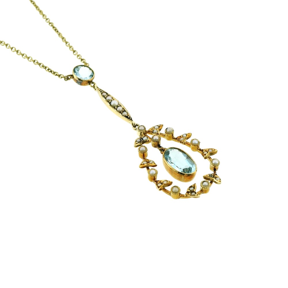 An Edwardian 15ct gold lavalier necklace featuring a round aquamarine top stone, a seed-pearl-set vertical bar, and a floral garland pendant surrounding a suspended oval aquamarine. View III
