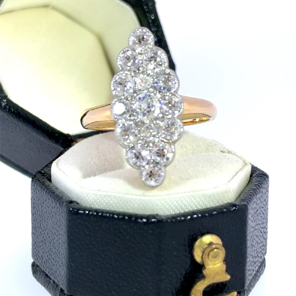 An Edwardian navette cluster ring featuring multiple old cut diamonds set in platinum with an 18ct yellow gold band.