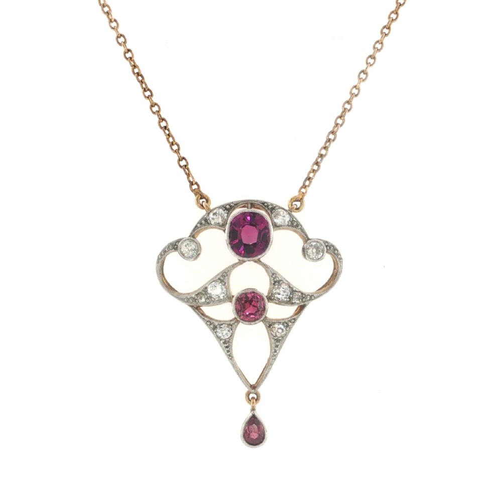 An Edwardian openwork 15ct gold and silver-topped pendant set with round rubies, diamond accents, and a pear-cut ruby drop on a gold chain. View II