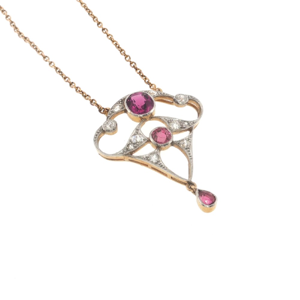 An Edwardian openwork 15ct gold and silver-topped pendant set with round rubies, diamond accents, and a pear-cut ruby drop on a gold chain. View III