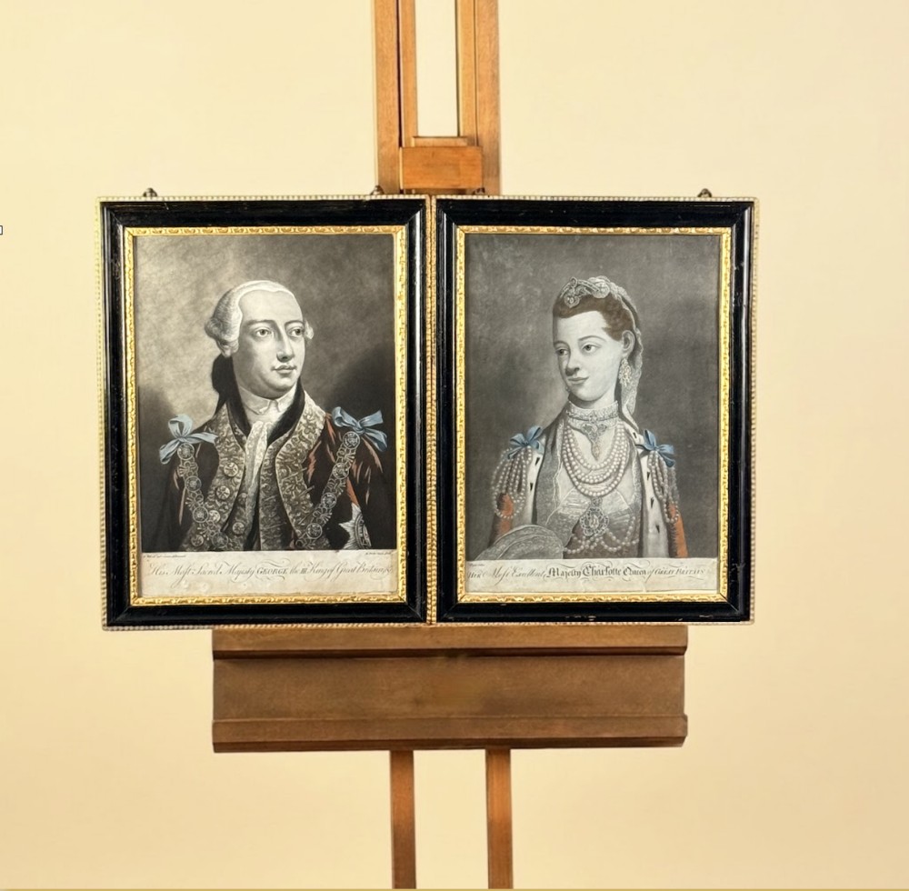 A framed pair of 18th-century monochrome mezzotint portraits depicting King George III and Queen Charlotte in decorative ebonised and gilt wood frames.