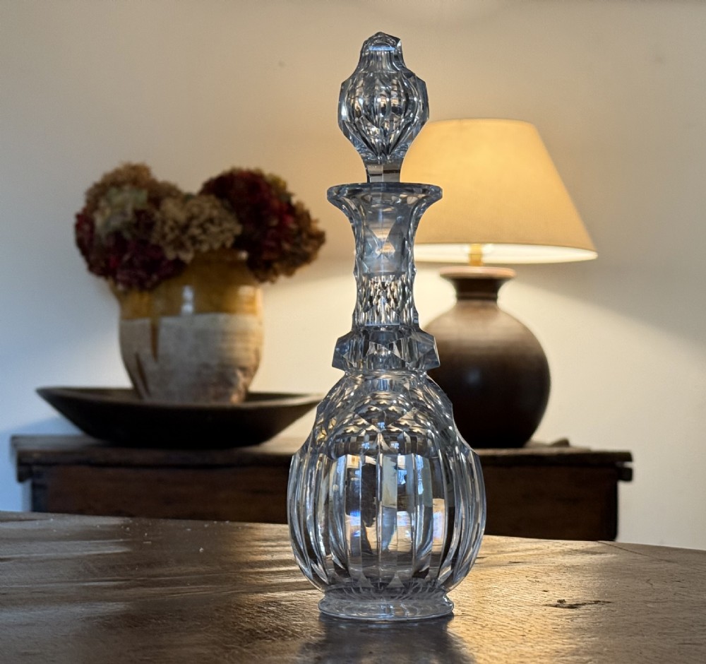 A Victorian clear cut glass liqueur decanter featuring a faceted stopper and geometric prism-cut details on the neck and bulbous body.