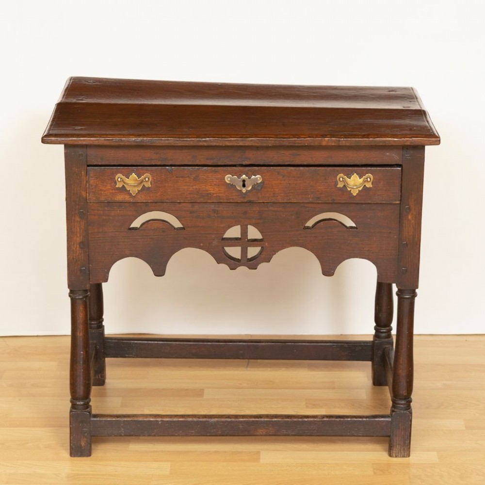 A Georgian dark oak side table featuring a single drawer with brass handles, a decorative pierced apron, turned legs, and a perimeter box stretcher. View II