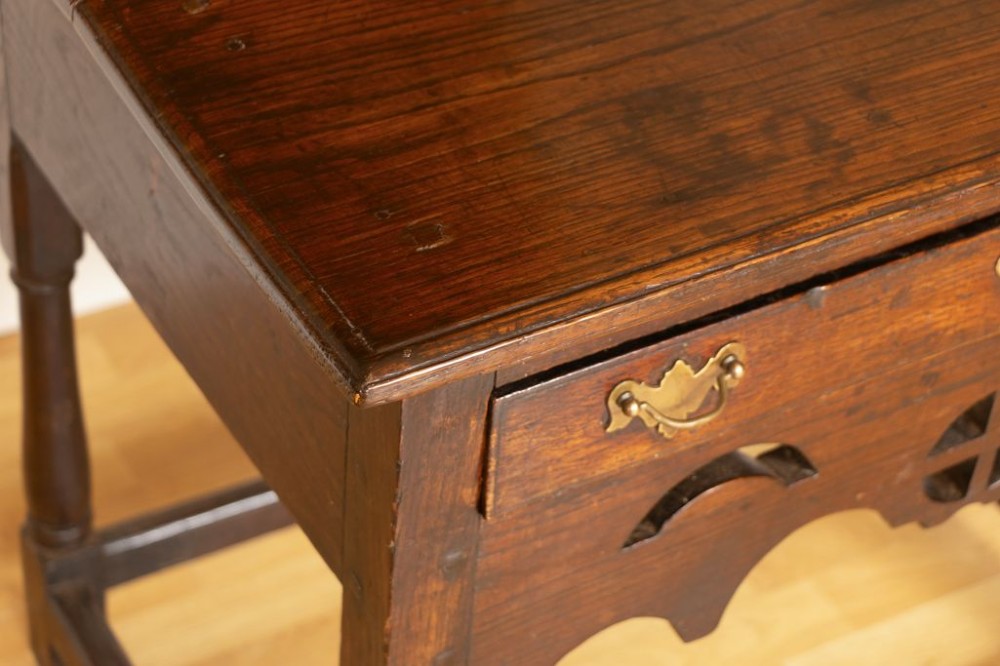 A Georgian dark oak side table featuring a single drawer with brass handles, a decorative pierced apron, turned legs, and a perimeter box stretcher. View III