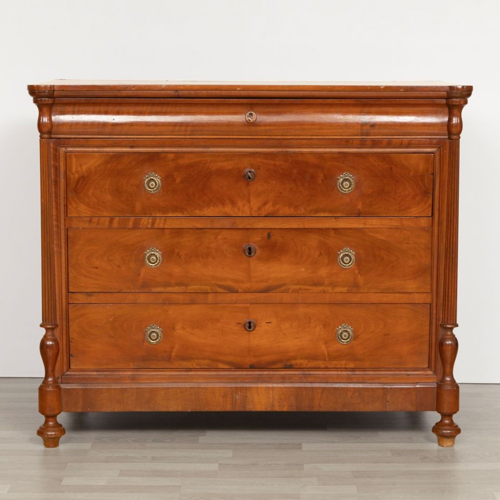 A 19th-century French walnut commode featuring four drawers, turned column side details, and brass keyhole escutcheons.