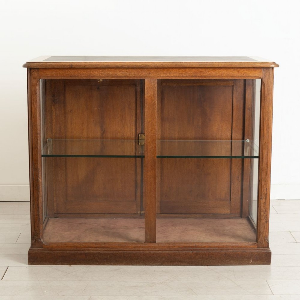 A late 19th-century French oak display case featuring clear glass front and side panels, a single interior glass shelf, and solid timber rear doors. View II