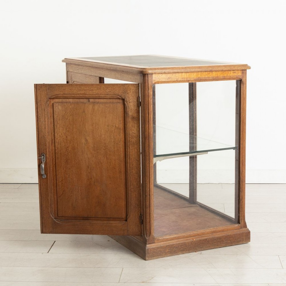 A late 19th-century French oak display case featuring clear glass front and side panels, a single interior glass shelf, and solid timber rear doors. View III