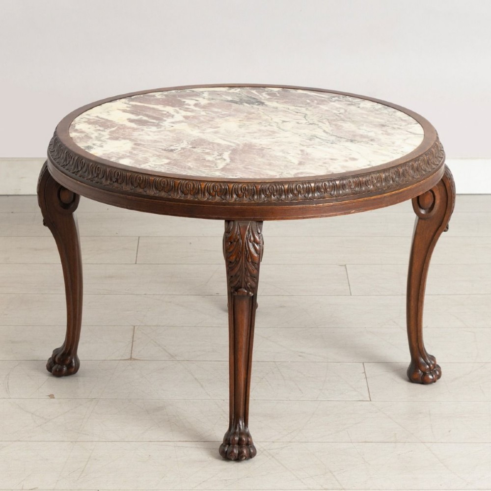 A round French walnut coffee table featuring a variegated pink and cream marble top, carved egg-and-dart moulding, and cabriole legs ending in claw-and-ball feet.