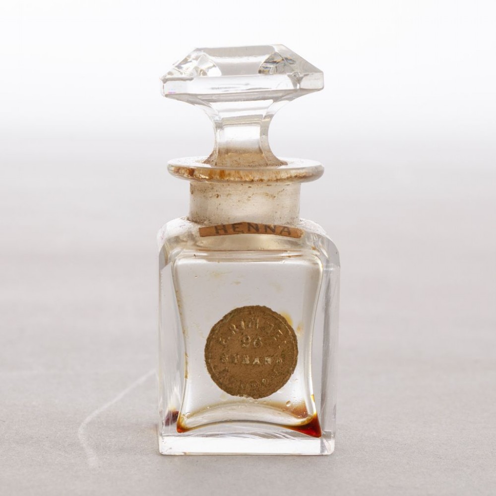 An open black leather box lined with purple velvet containing three clear glass perfume bottles with octagonal faceted stoppers. View IV
