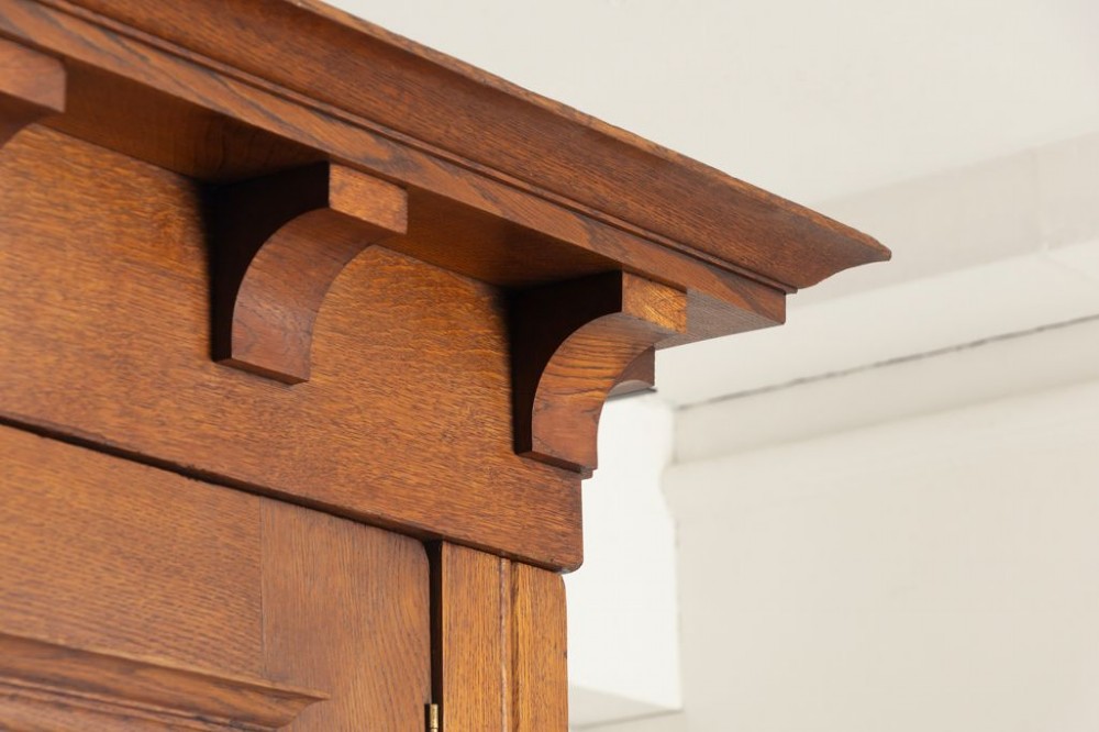 A large oak three-door Arts and Crafts wardrobe featuring a central arched mirror flanked by stylized inlaid panels over two lower drawers. View V