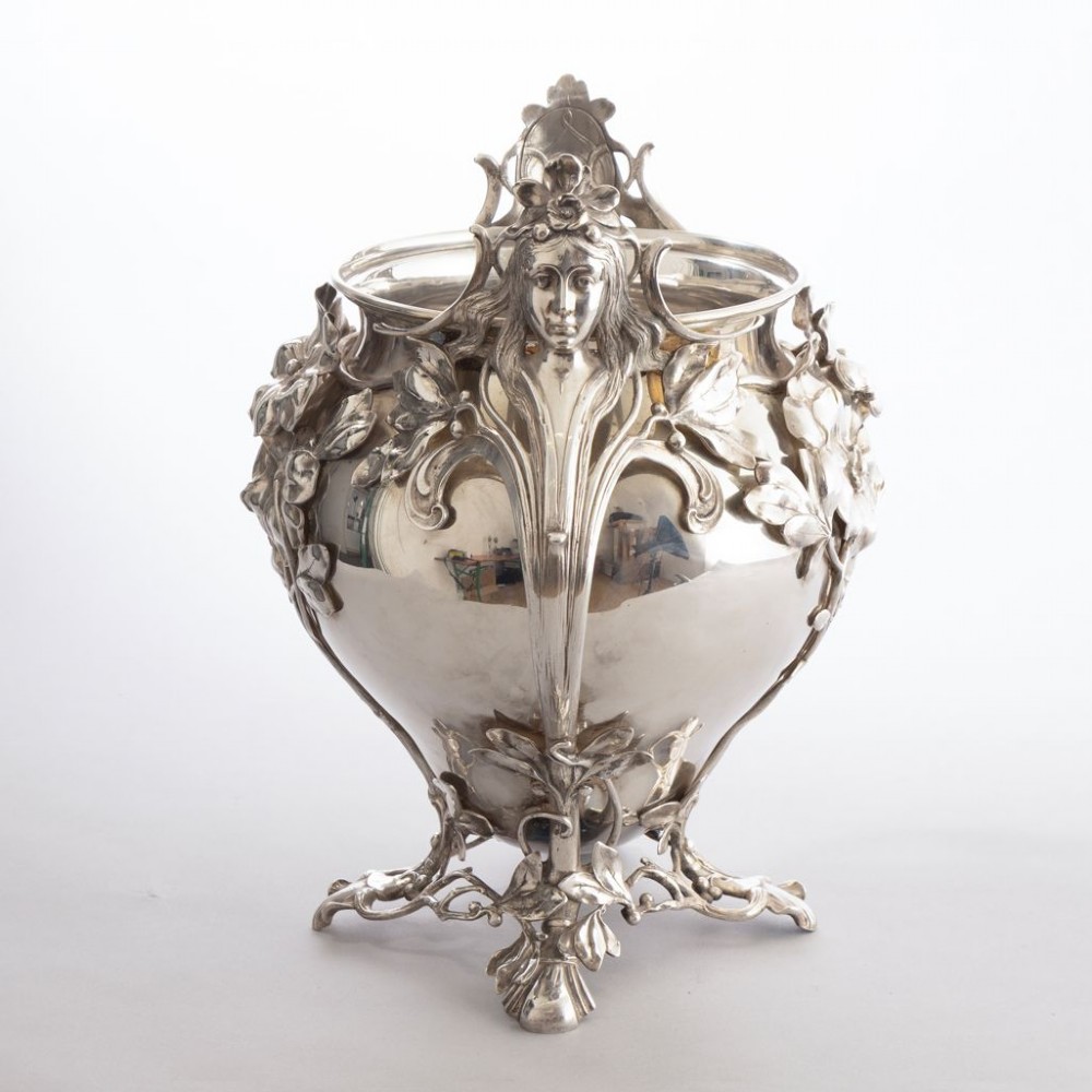 A silver-plated Art Nouveau champagne bucket featuring floral relief details, whiplash tendrils, sculpted handles with female heads, and a pierced footed base. View II