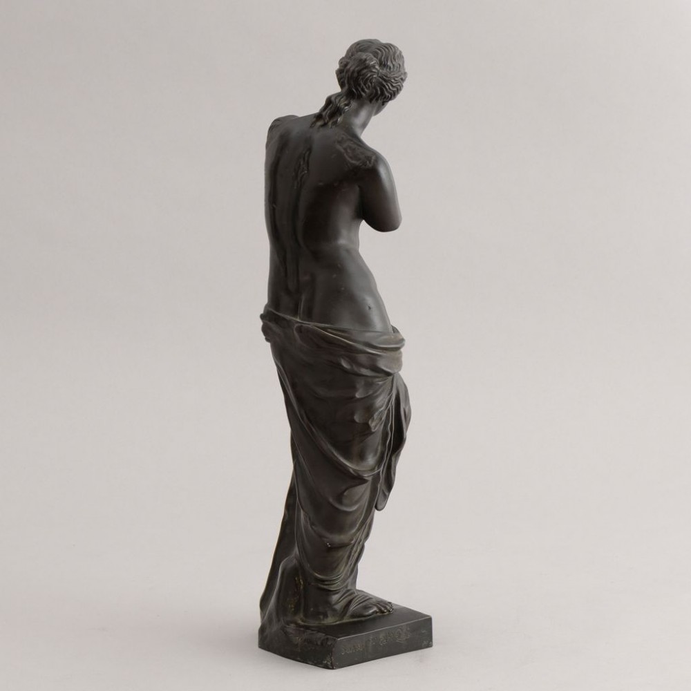 A dark brown bronze sculpture depicting the Venus de Milo draped in cloth around the lower body, mounted on an integrated rectangular base. View IV