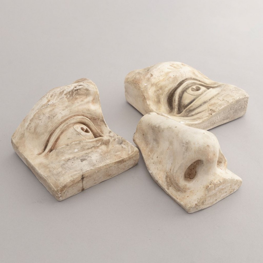 Three 19th-century aged off-white plaster casts displaying sculpted anatomical features including eyes and a nose after Michelangelos David.