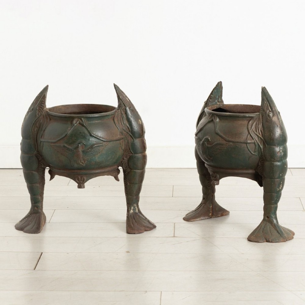 A pair of dark green cast iron planters designed as rounded vessels supported by three carved shrimp legs with relief bird motifs.