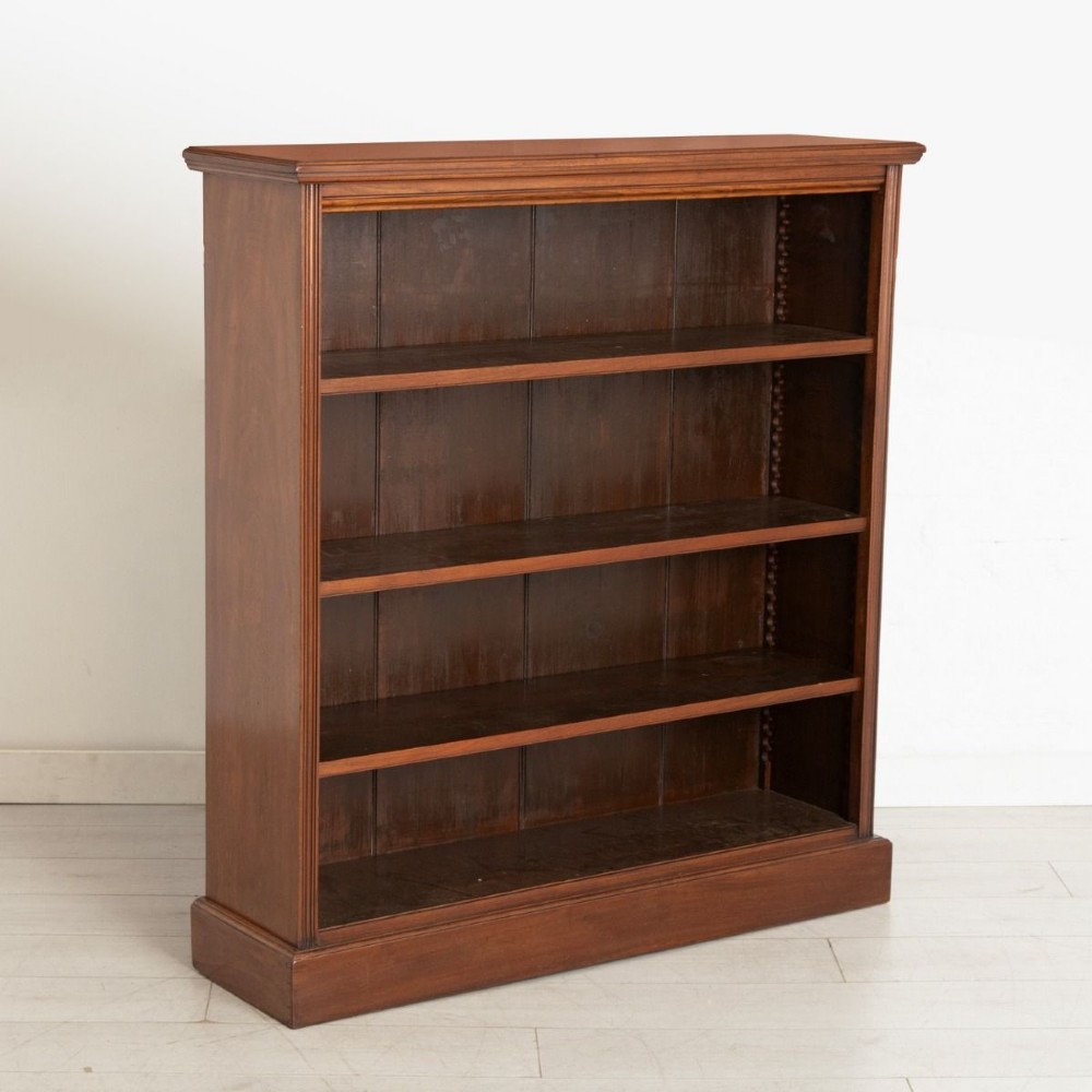 A Victorian walnut open bookcase featuring three adjustable shelves, fluted side pilasters, and a solid plinth base.