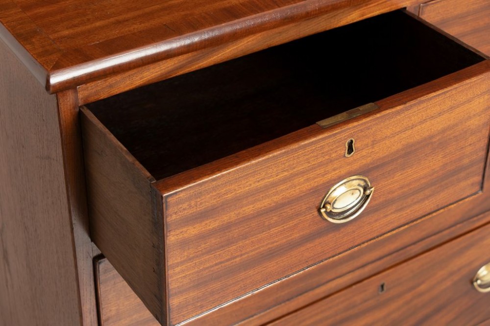 A small Georgian mahogany chest of drawers featuring two short drawers over two long drawers with brass oval handles and splayed feet. View III