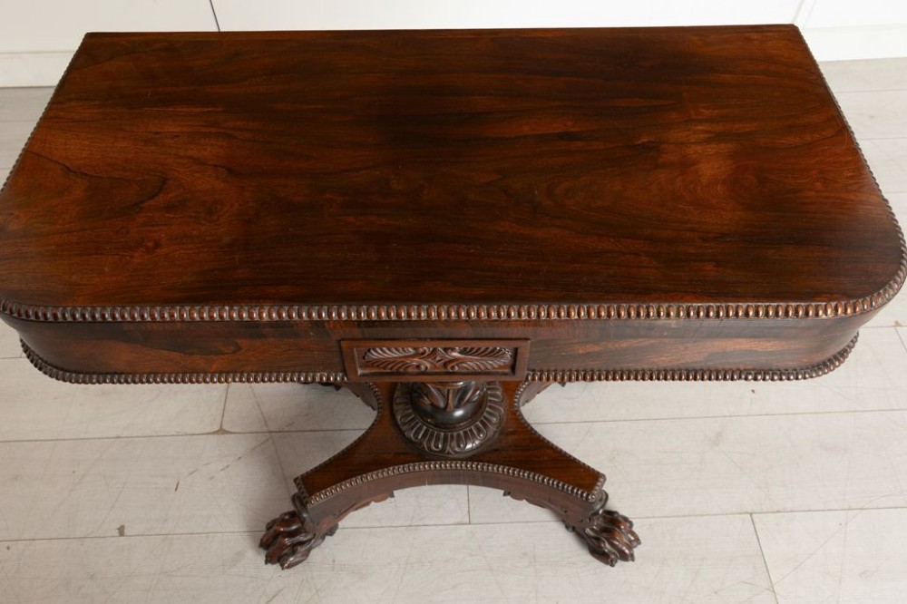 An antique mahogany gaming table featuring an unfolded green baize playing surface supported by a central carved pedestal stem and quadform base. View IV