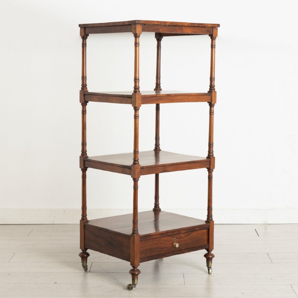 A 19th-century rosewood four-tier whatnot featuring turned columns, a single base drawer with brass knob, and brass castors.