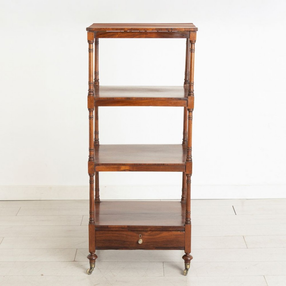 A 19th-century rosewood four-tier whatnot featuring turned columns, a single base drawer with brass knob, and brass castors. View II