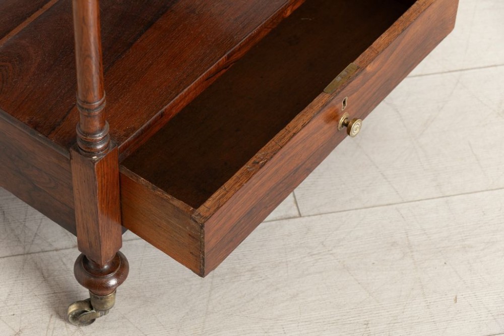 A 19th-century rosewood four-tier whatnot featuring turned columns, a single base drawer with brass knob, and brass castors. View III