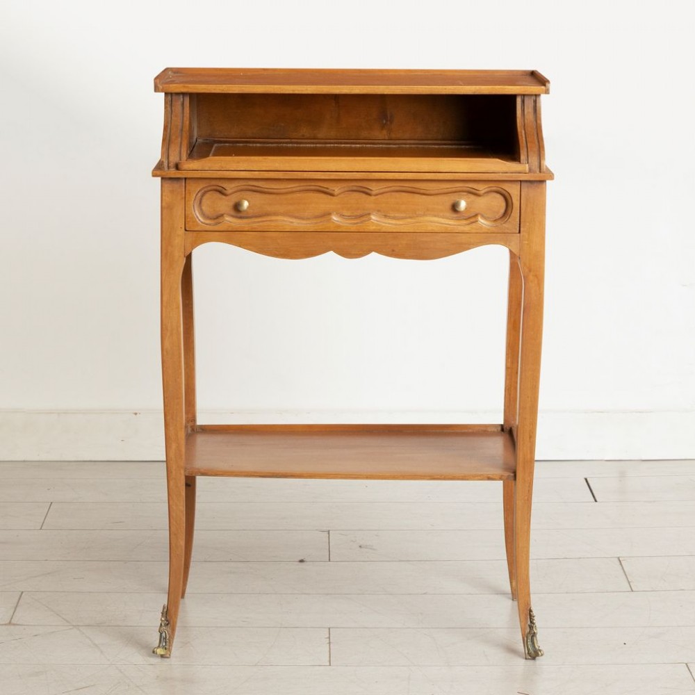 A small French provincial style fruitwood writing table with an upper gallery shelf, single drawer, lower tier shelf, cabriole legs, and brass sabot feet. View II