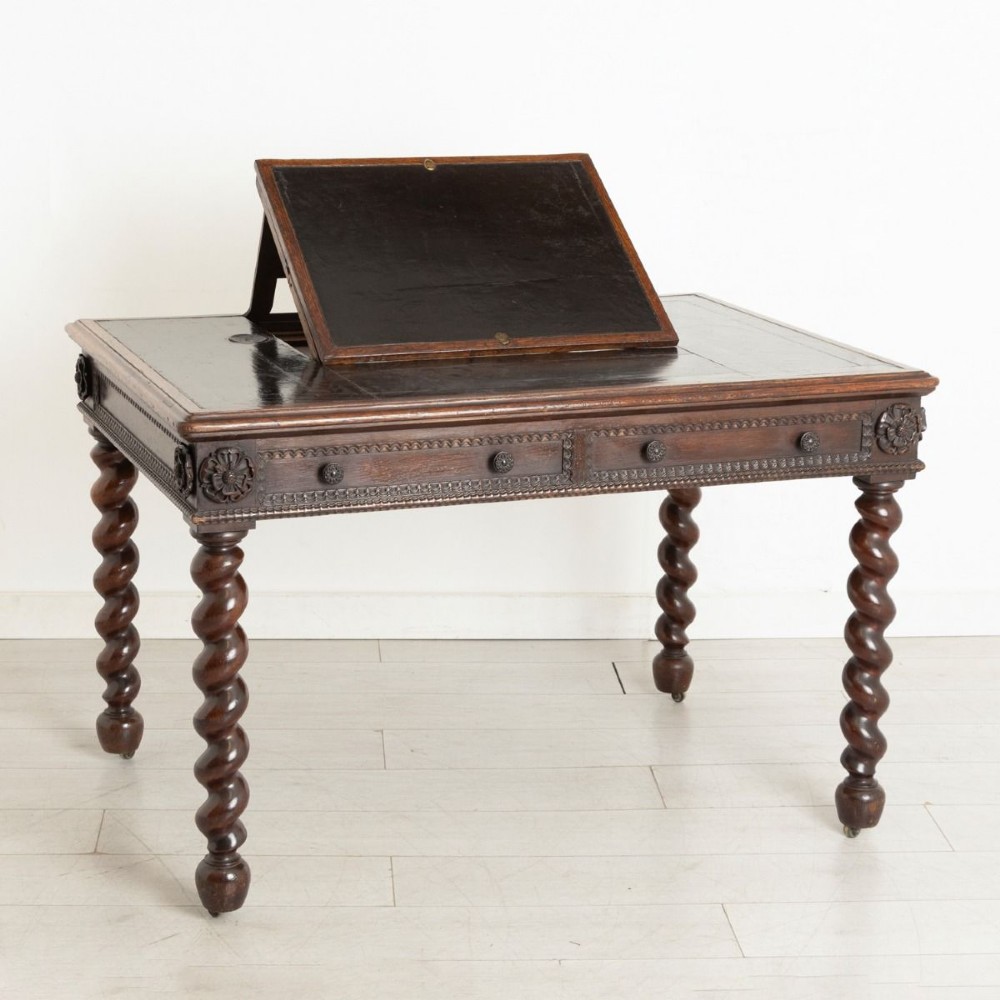 A nineteenth-century dark oak Neo-Jacobean architect desk with barley twist legs, carved decorative frieze, and an adjustable central leather writing slope.