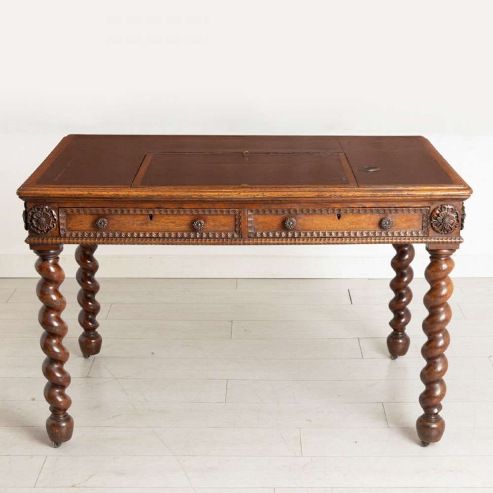 A nineteenth-century dark oak Neo-Jacobean architect desk with barley twist legs, carved decorative frieze, and an adjustable central leather writing slope. View II