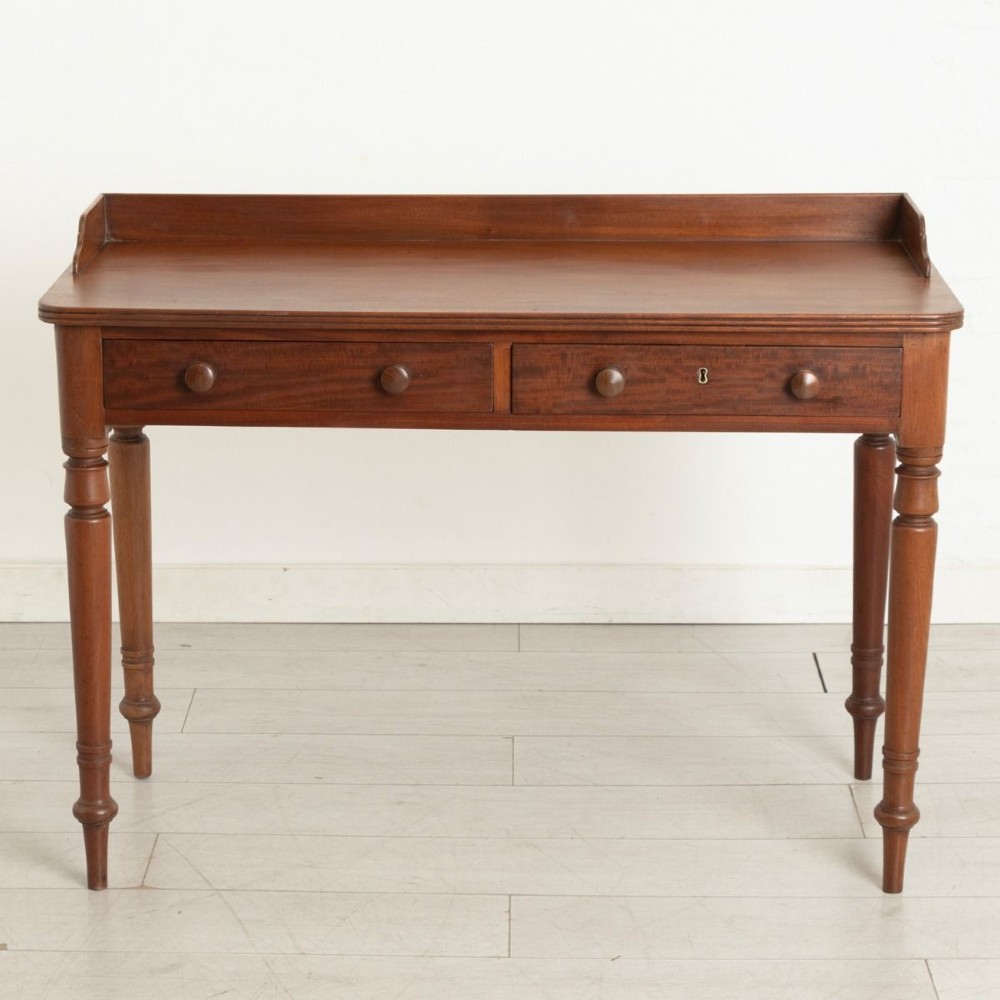 A 19th-century solid mahogany writing table featuring two frieze drawers with turned wooden handles and a low rear gallery.
