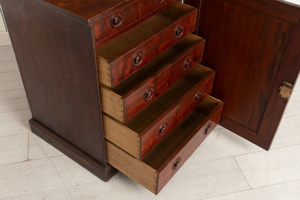 A dark mahogany musicians cabinet with an open single panel door revealing five shallow drawers with turned circular knobs. View III