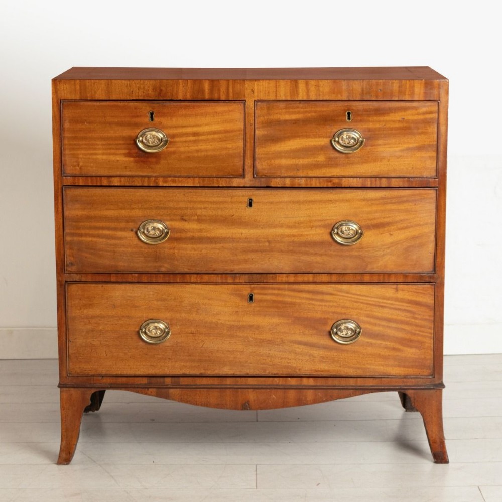 An antique Regency mahogany chest of drawers featuring two short drawers above two long drawers with brass handles and splayed bracket feet.