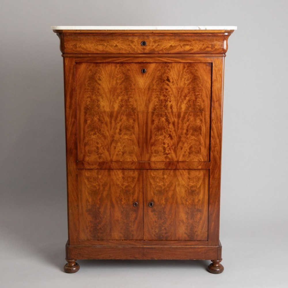 A 19th-century French Louis Philippe flame mahogany secretaire a abattant featuring a white marble top, upper frieze drawer, drop-front writing flap, and lower double doors.